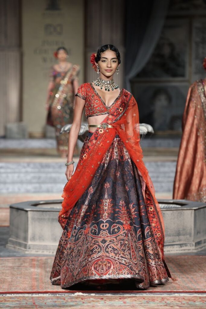 Indian model walking the runway in a stunning floral saree during a fashion show.