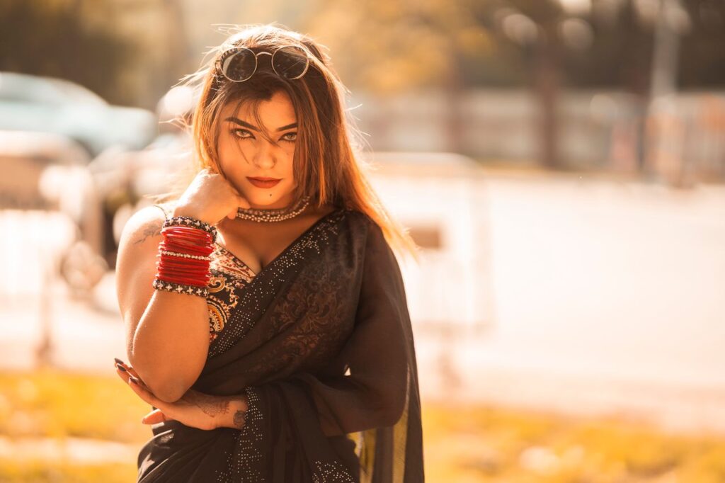 Portrait of a confident Indian woman in traditional saree, outdoors in warm daylight.