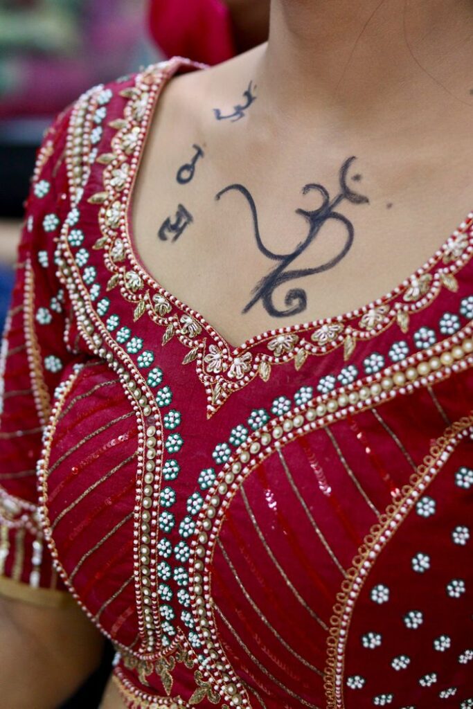 Close-up of a red traditional Indian dress with embroidery details and neck tattoo.
