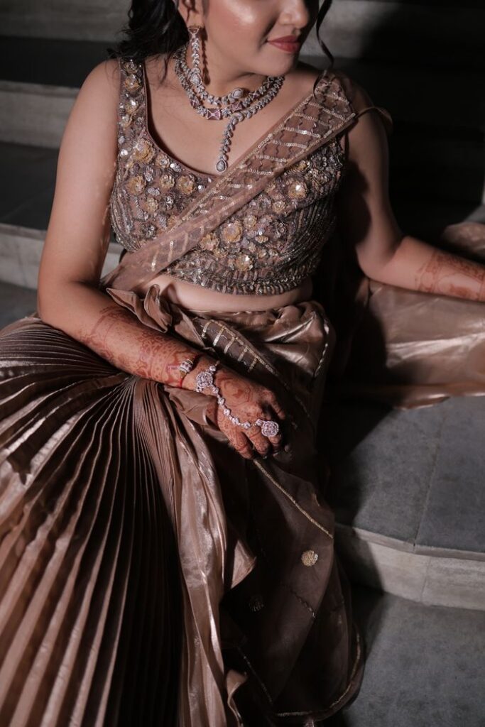 A woman elegantly dressed in traditional Indian attire with intricate jewelry and mehndi on her hands.