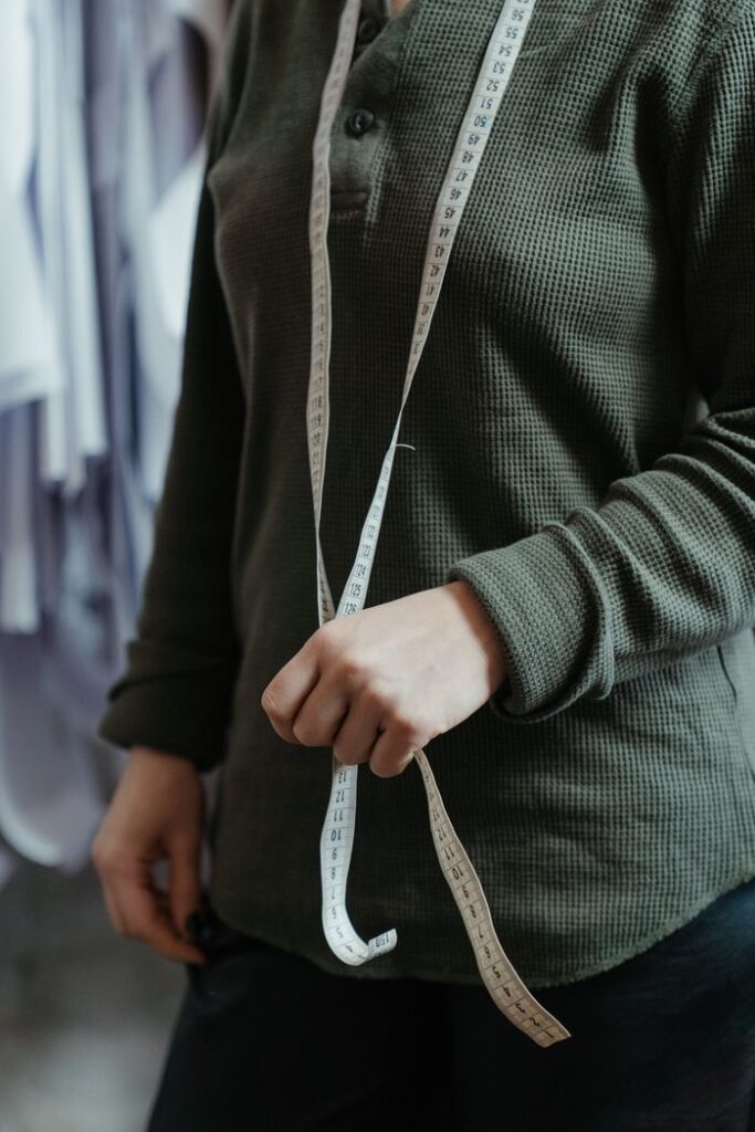 Female tailor with measuring tape in a fashion studio, emphasizing the profession's precision.