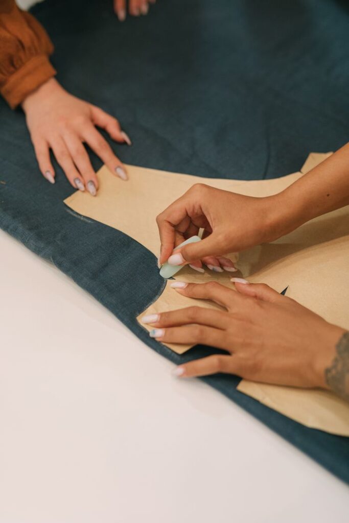 Close-up of hands marking a garment pattern, showcasing the craft of tailoring.