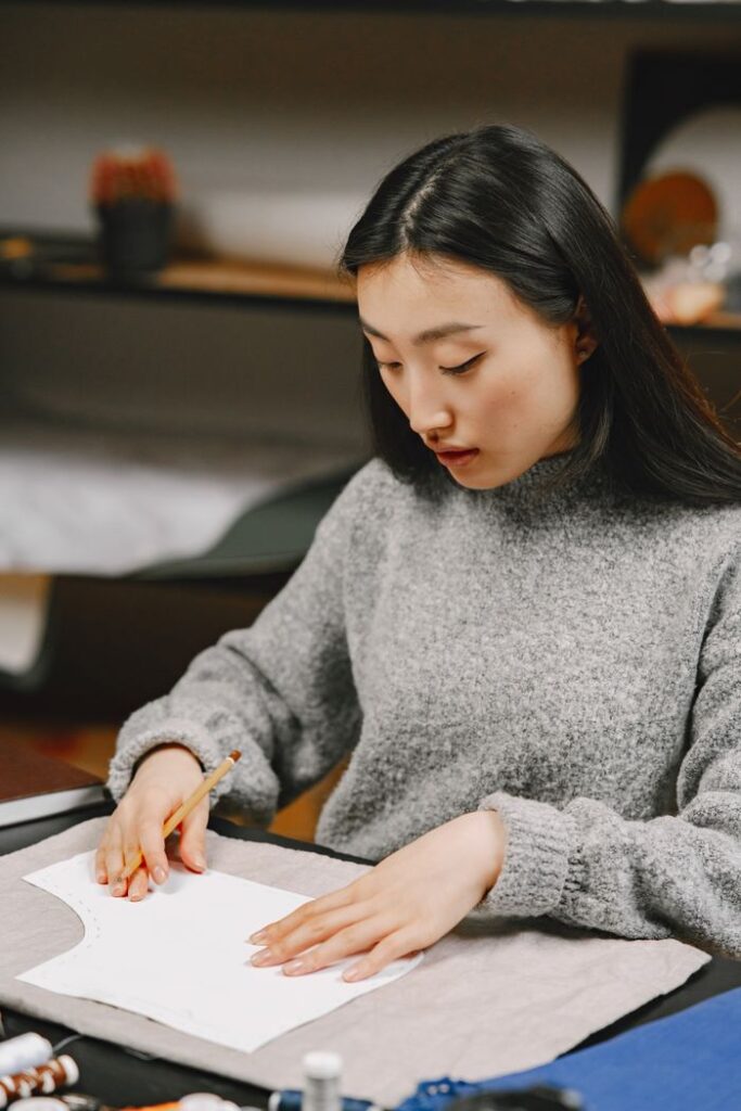 Focused woman cutting fabric, showcasing crafting skills in a cozy workshop.