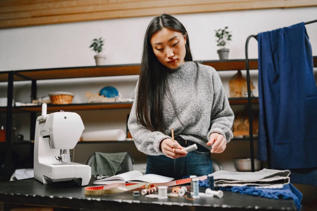 Focused woman tailor measuring fabric and preparing for dressmaking in a studio.