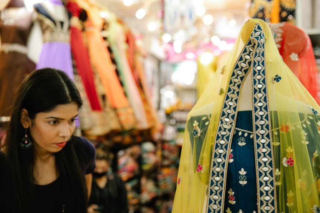 Woman explores a lively bazaar showcasing colorful traditional dresses.